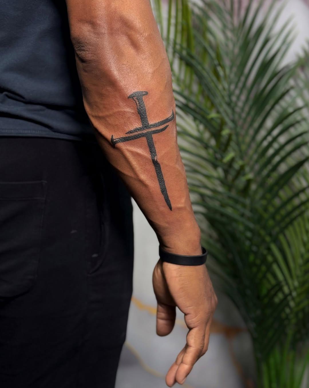Nail cross tattoo on forearm